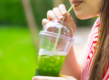 woman sipping iced green beverage outside