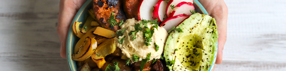 A bowl of roated vegetables, hummus and avocado